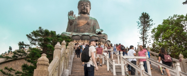 Tourists standing on the steps leading up to 'The Big Buddha' statue on Lantau Island, Hong Kong.